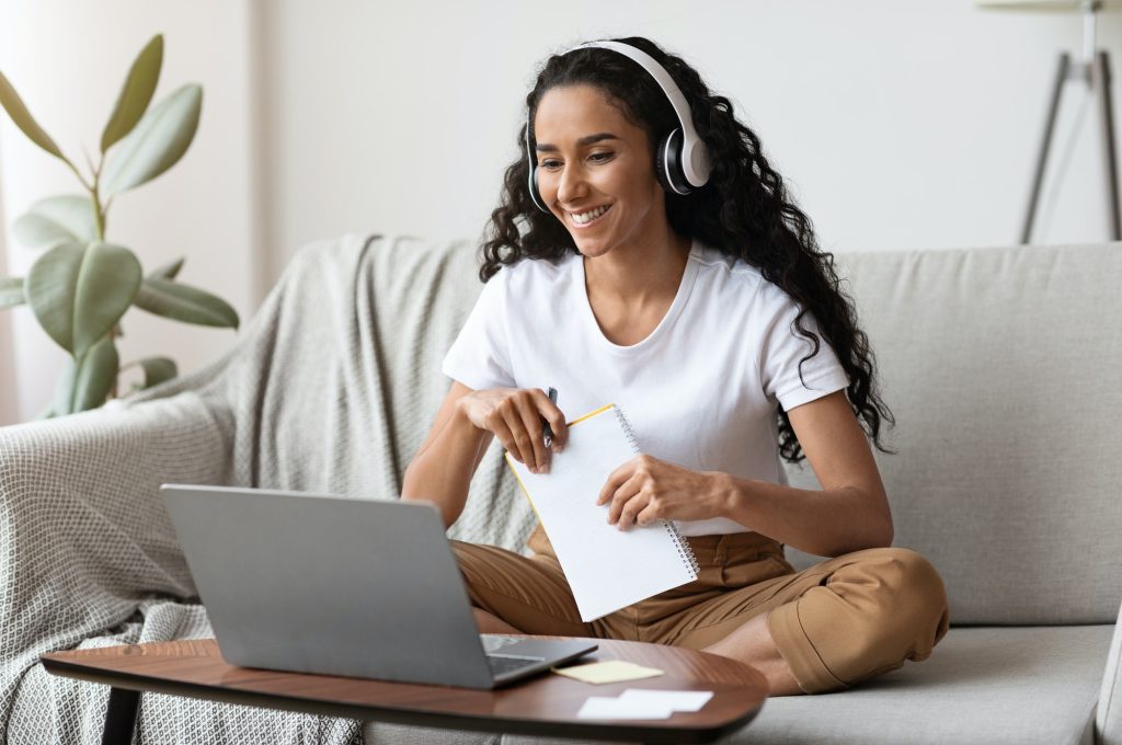 cheerful-lady-attending-online-course-using-laptop-and-wireless-headset